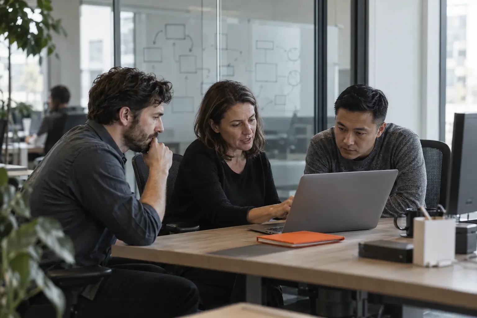 A delivery manager and two engineers talk through a laptop at a desk.